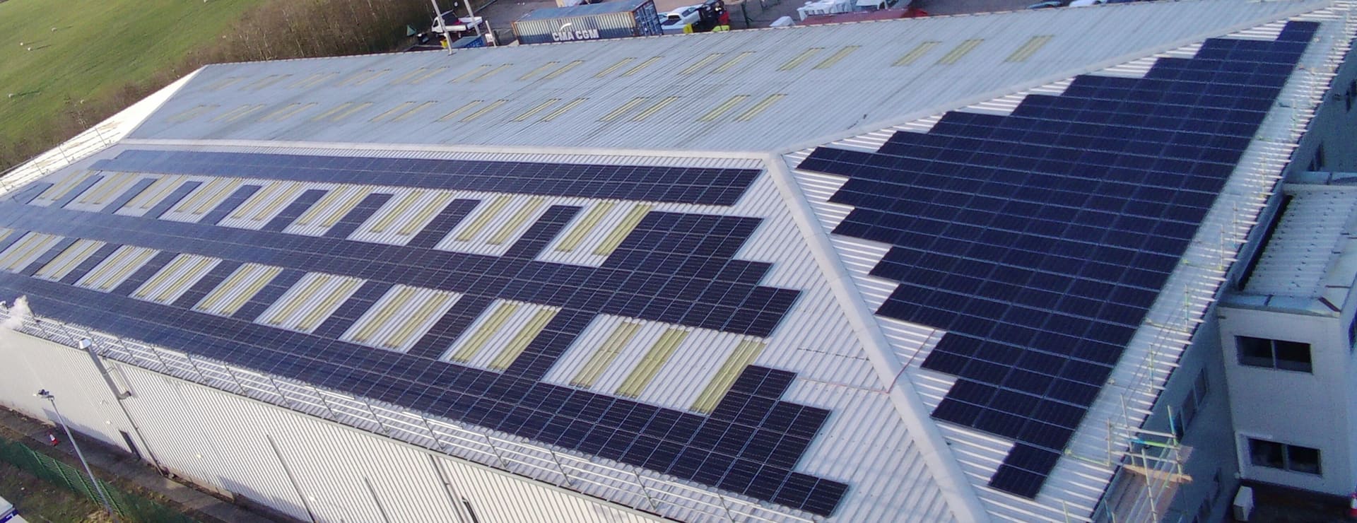 Aerial panorama of a Green Tech Hub commercial rooftop solar installation across an industrial roof