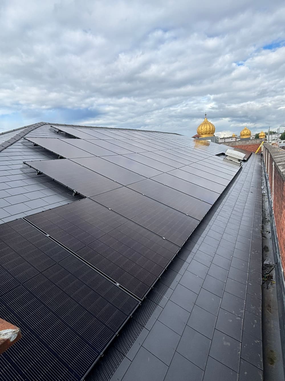 Solar panels on the Gurdwara roof with the golden domes beyond